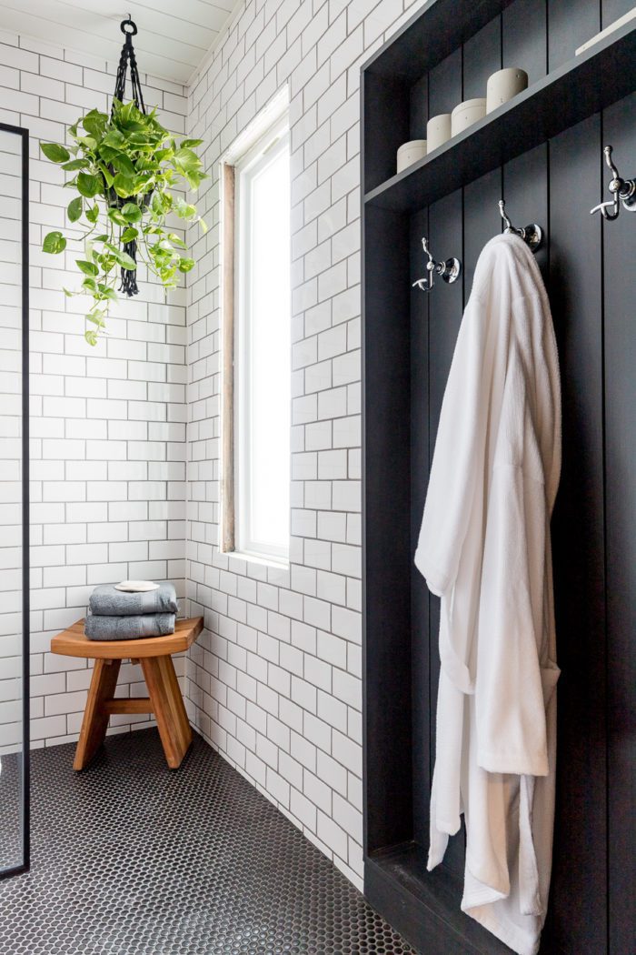 Industrial bathroom featuring white subway tile, black vertical shiplap and black hexagon flooring. 