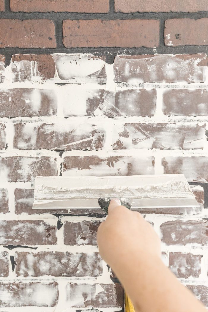 Add sheetrock compound to faux brick wall panels to give it a realistic appearance. 