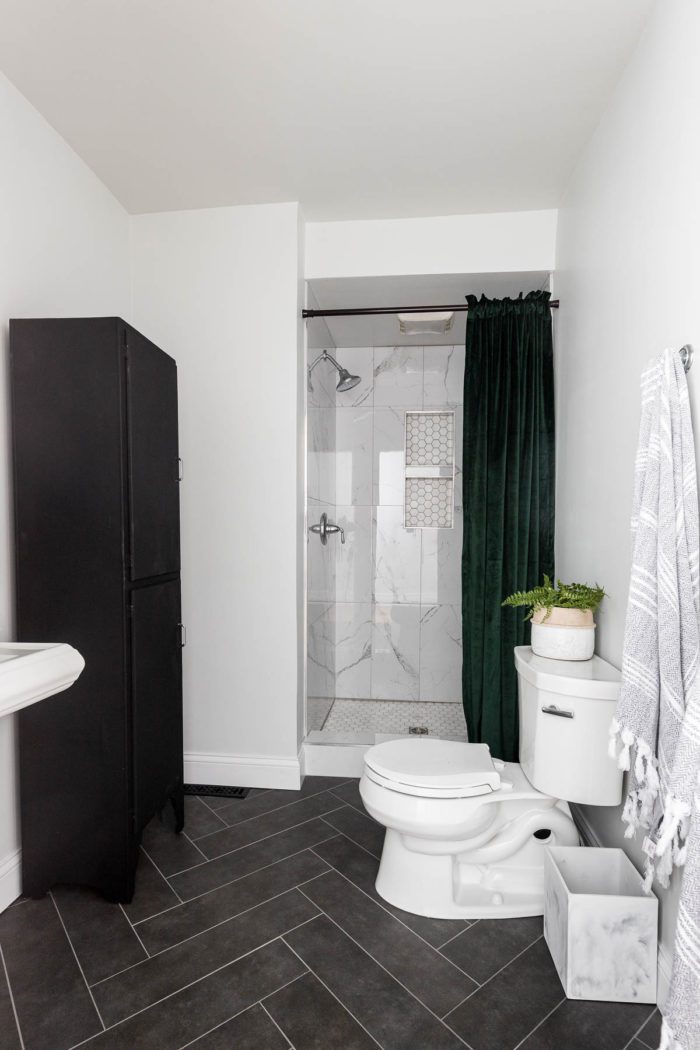 Small Bathroom renovation, stand up shower with marble tile and black herringbone floors.