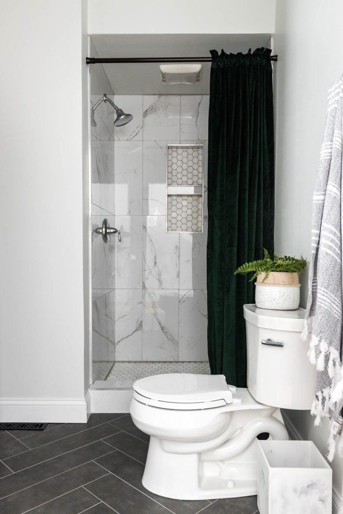 Marble tile in shower with green velvet shower curtain