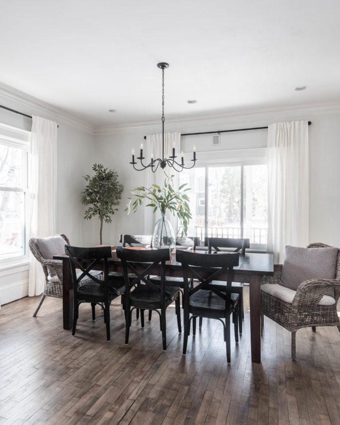 Dark dining room table with black chairs and white curtains. 