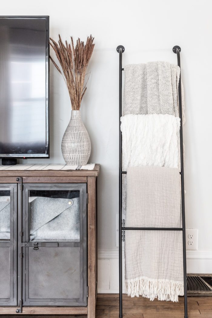 Blanket ladder next to tv stand with Fall Decor.