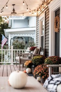 Fall front porch with pumps around the door and cafe lights hanging on the ceiling