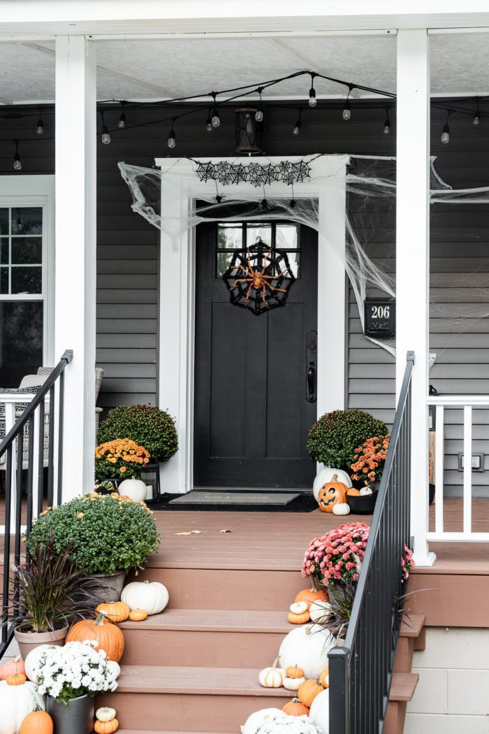 Black front door with halloween spider wreath and webs. 