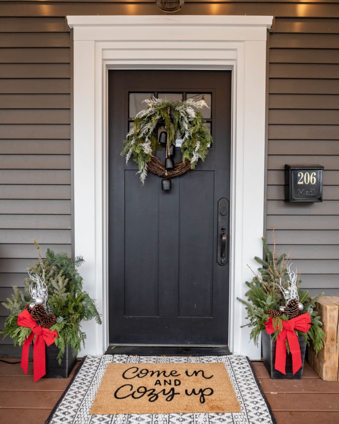 Black front door with Christmas wreath and decor. 