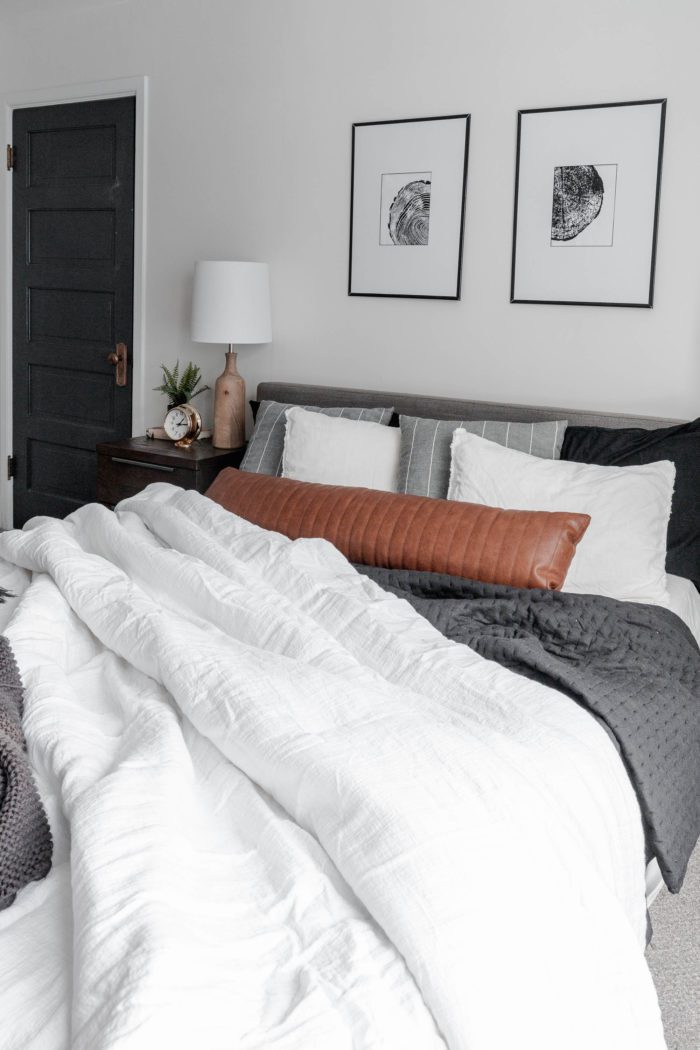 How to Make Your Bed like a Designer Queen size bed with a modern gray headboard, white bedding, dark gray accents and a leather lumbar pillow. All with a messy, cozy, lived in look! 