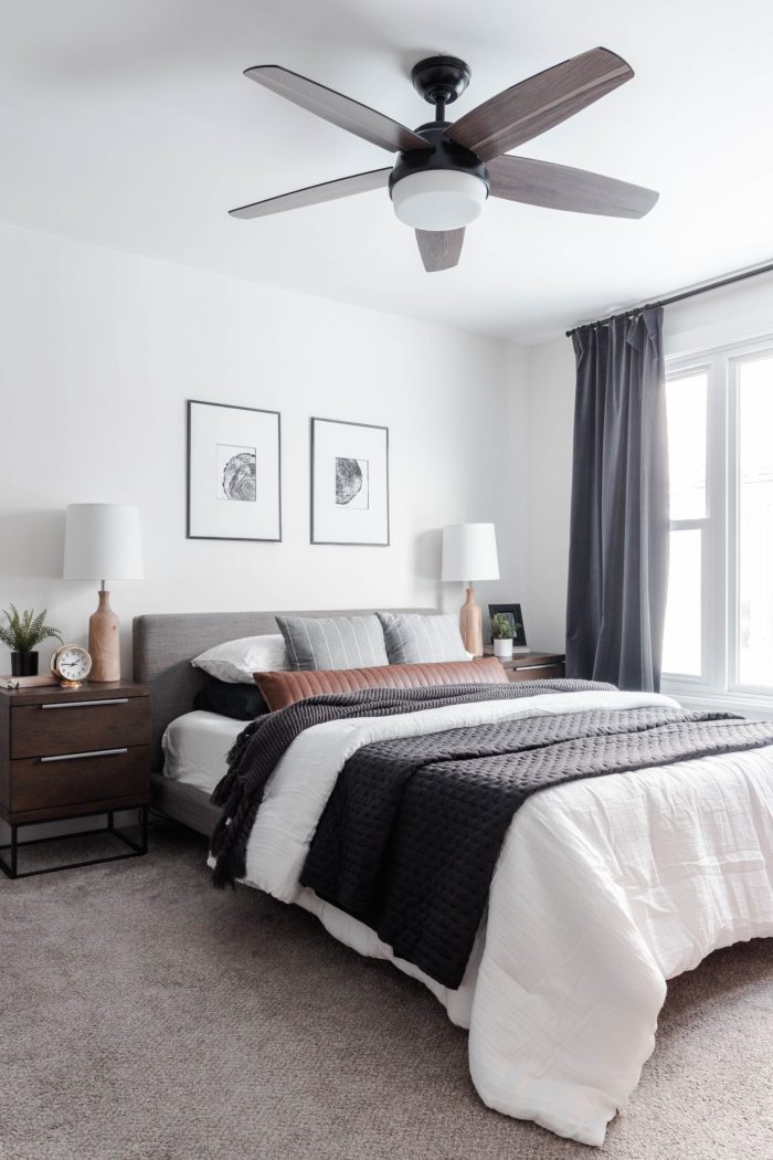 How to Make Your Bed like a Designer: Queen size bed with a modern gray headboard, white bedding, dark gray accents and a leather lumbar pillow.