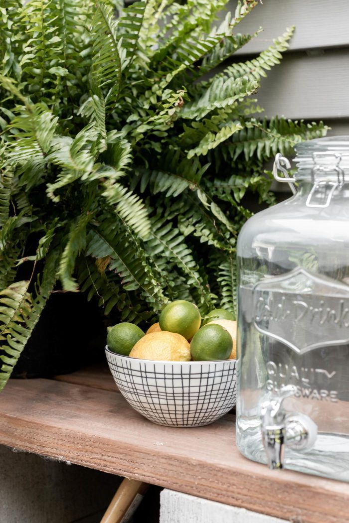 Fresh lemons and limes in a modern glass bowl served next to a glass water dispenser