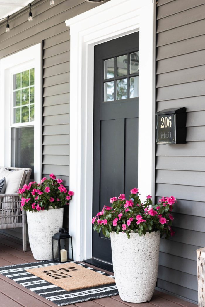 Tall planters on either side of front door with layered rugs creating the perfect summer spot! 