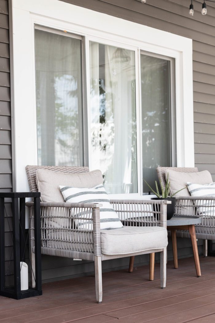 Outdoor furniture on front porch decorated for summer. 