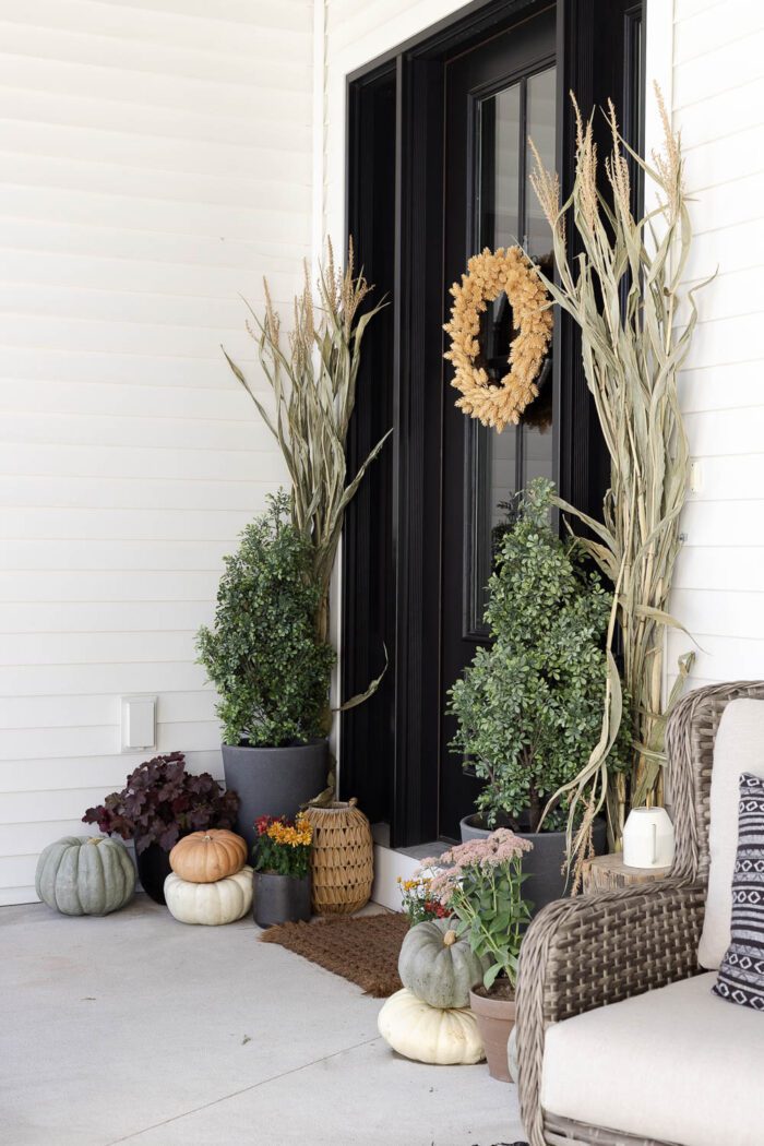 Fall front porch with black door, pumpkins and fall plants. 